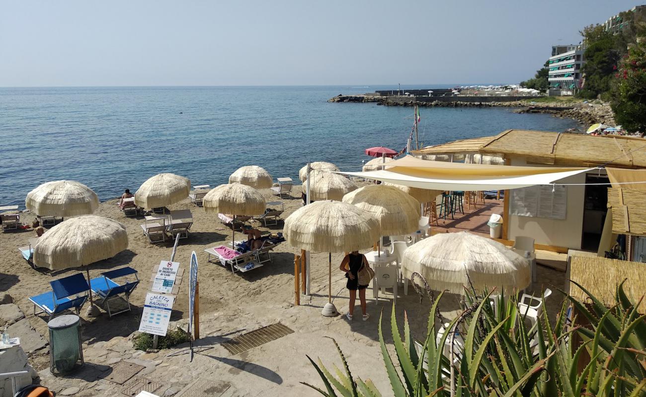 Photo of Caletta del Bagnino with gray sand &  rocks surface