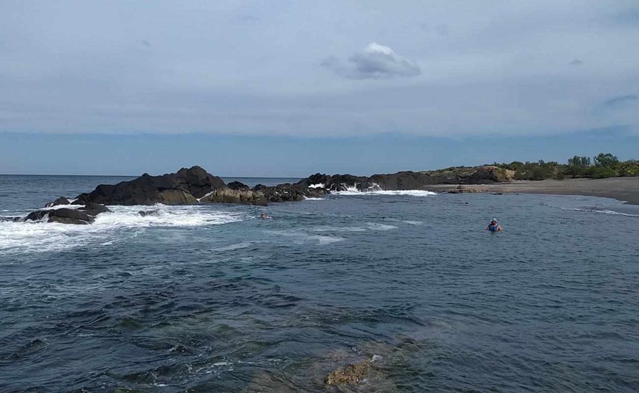 Photo of La Mona beach with gray sand &  rocks surface