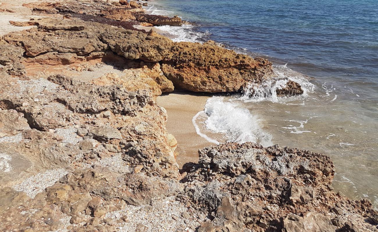 Photo of Cala l'Arjub with brown sand &  rocks surface