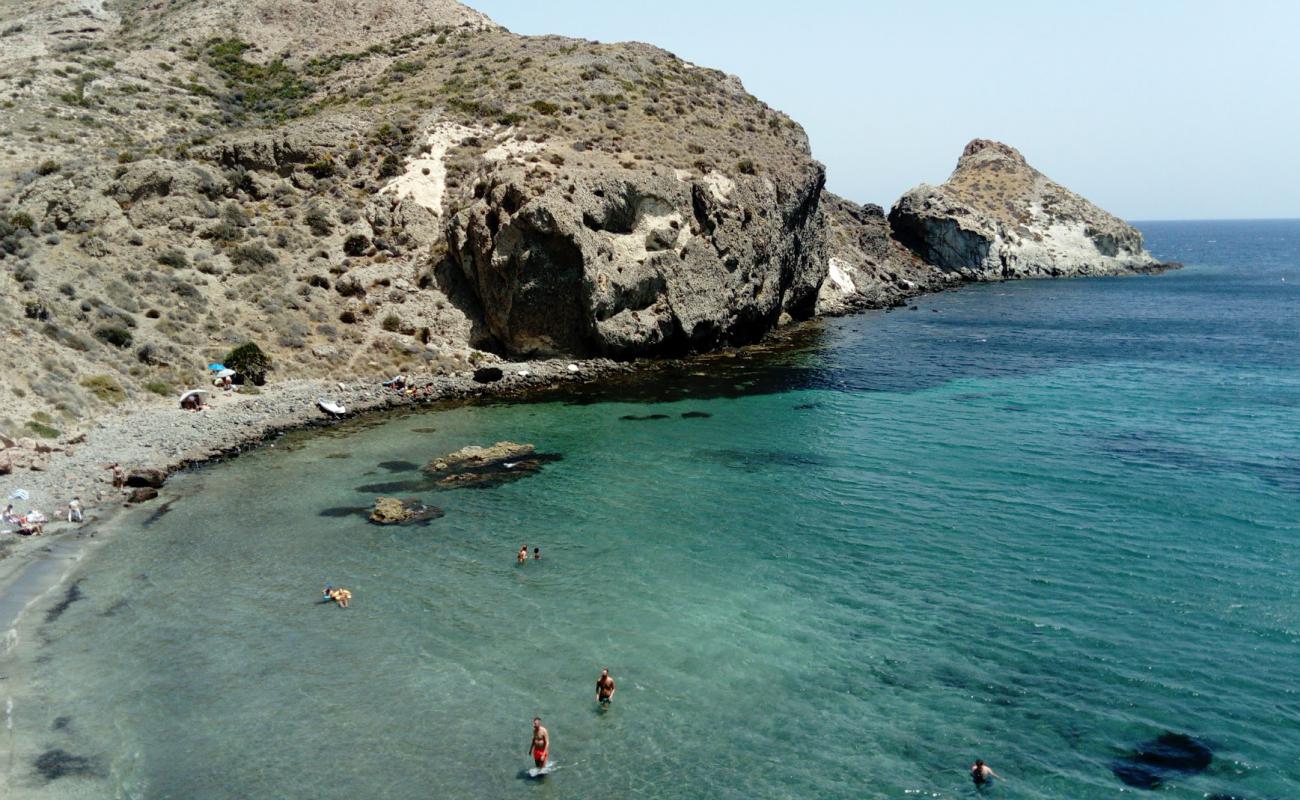 Photo of Cala Higuera with brown pebble surface