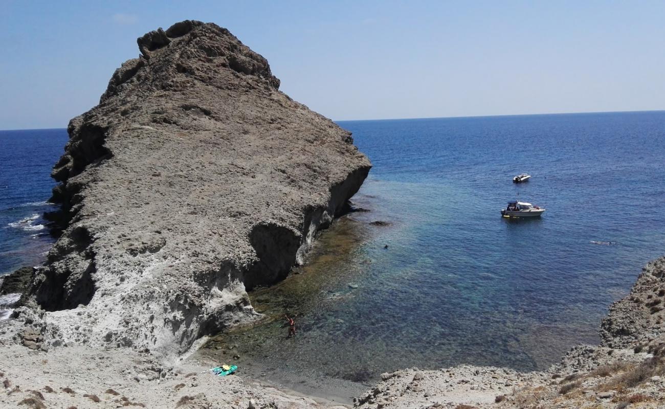 Photo of Cala de las Hermanicas with gray sand &  rocks surface