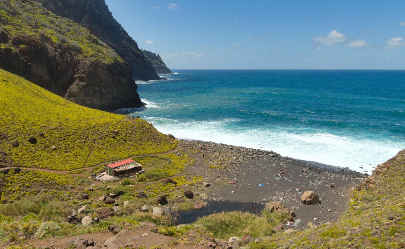 Photo of Playa Tamadiste with gray sand &  rocks surface